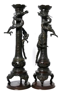 Lot 270 - A pair of Japanese bronze candlesticks, Meiji, applied with sinuous dragons on trefoil feet and...