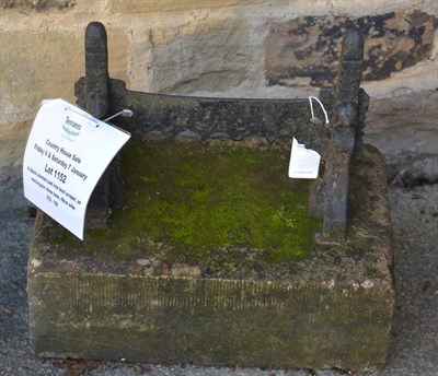 Lot 1152 - A black painted cast iron boot scraper, on rectangular stone base, 48cm wide