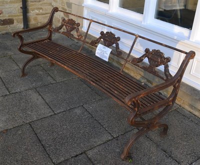 Lot 1155 - A pair of cast iron curved garden benches of classical design, the backs decorated with urns...