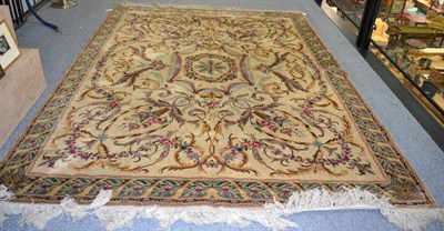 Lot 1195 - A carpet of Savounnerie design, the cream field of scrolling acanthus leaves and garlands...