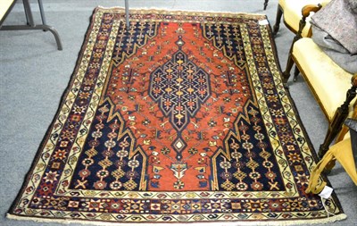 Lot 1209 - Mazlaghan rug, West Iran, the terracotta field of lightening design around an indigo medallion...