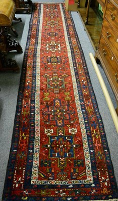 Lot 1218 - Narrow Heriz runner, Iranian Azerbaijan, the deep terracotta field with a row of cruciform...