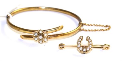 Lot 102 - A seed pearl bangle, formed of two cross over bars with a central floral cluster set with seed...