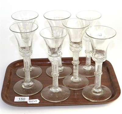 Lot 150 - A matched set of seven wine glasses, circa 1750, the air twist stems with grilled collars,...