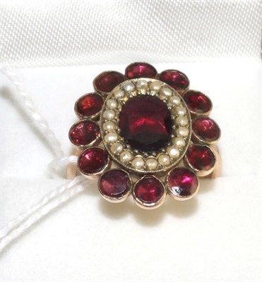 Lot 312 - A garnet and seed pearl cluster ring, an oval cut garnet in a yellow claw setting within a...