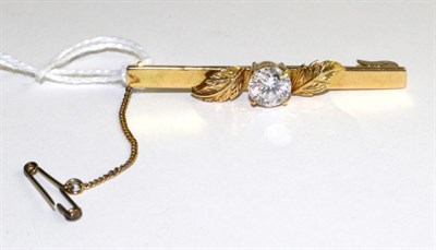 Lot 313 - A cubic zirconia bar brooch, a round brilliant cut cubic zirconia in a yellow four claw setting...