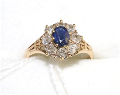 Lot 321 - An 18 carat gold sapphire and diamond cluster ring, an oval cut sapphire within a border of old cut