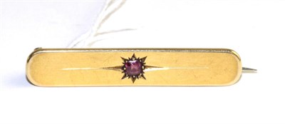 Lot 332 - An 18 carat gold bar ruby bar brooch, a round cut ruby in a star setting to a plain bar, length...