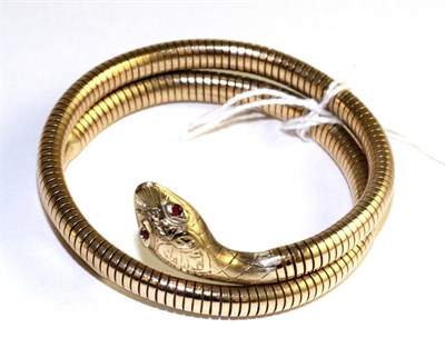 Lot 341 - A 9 carat gold snake bangle, with faceted ruby eyes and foliate engraved head to a coiled...