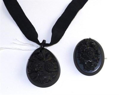 Lot 351 - A carved jet pendant, of oval form and carved in high relief with a floral spray, on a black fabric