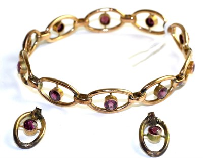 Lot 379 - A garnet bangle, round cut garnets in yellow milgain settings, to pierced oval links, measures...