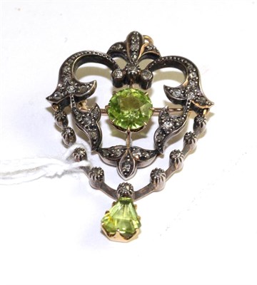 Lot 512 - An Art Nouveau peridot and diamond pendant/brooch, the openwork scroll frame set throughout with od