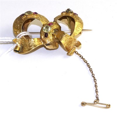 Lot 513 - A gem set bow brooch, with chased floral decoration and set with groups of faceted chrysoberyl...