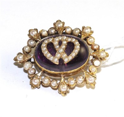 Lot 519 - An amethyst and seed pearl brooch, an oval cabochon amethyst with applied seed pearl set twin heart