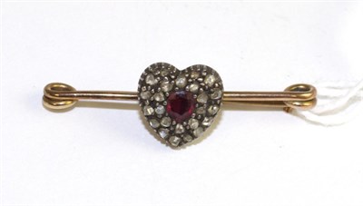 Lot 572 - A ruby and diamond heart brooch, an oval cut ruby within a heart shaped cluster set throughout with