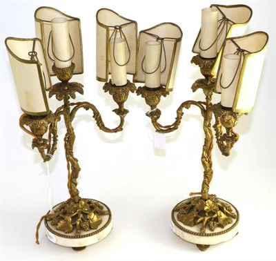 Lot 644 - A pair of gilt metal three-light candelabra, late 19th century, cast with fruiting vine on circular