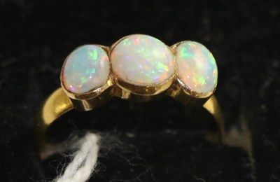 Lot 726 - An opal three stone ring, a round cabochon opal between two oval cabochon opals in yellow...