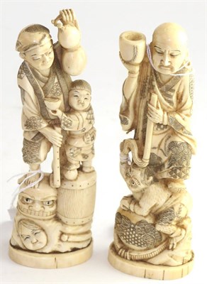 Lot 796 - A Japanese ivory okimono as a man holding a double gourd a boy at his side standing on a drum...