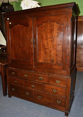 Lot 1256 - {} An 18th century oak chest cupboard with two cupboard doors enclosing hanging space above...