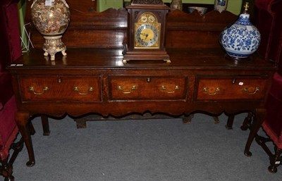 Lot 1294 - {} An 18th century oak and mahogany cross banded low dresser raised on cabriole four legs,...