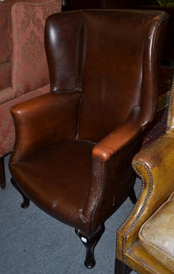 Lot 1296 - ^ A late George III wing back armchair, upholstered in close nailed brown leather raised on...