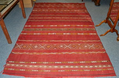 Lot 1301 - A Moroccan flat weave carpet, North West Africa, the madder field with narrow bands of...