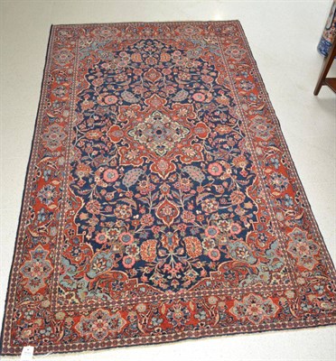 Lot 1356 - Gasvin rug, West Iran, the indigo floral vine field centred by a brick red medallion framed by...