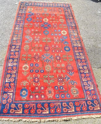 Lot 1372 - East Turkestan rug, Khotan, the abrashed crimson field of angular vines enclosed by indigo...