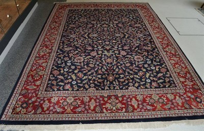 Lot 1374 - Indian carpet, the indigo field with an allover design of scrolling vines enclosed by brick red...