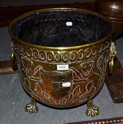 Lot 1402 - An embossed brass 19th century log bin, raised on three lion feet supports, 42cm diameter