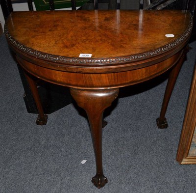 Lot 1530 - A 1920s figured walnut foldover card table, raised on four cabriole legs with ball and claw...