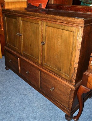 Lot 1624 - ~ A 1930's oak sideboard fitted with three cupboard doors, 133cm wide