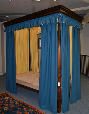 Lot 1660 - A four poster bedstead with reeded and carved foot posts, hung with blue curtains lined in...