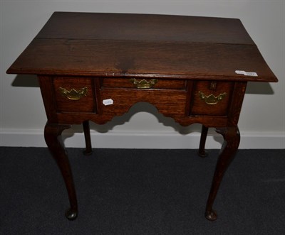 Lot 1687 - {} An 18th century oak lowboy with three frieze drawers above an arched apron, 76cm wide