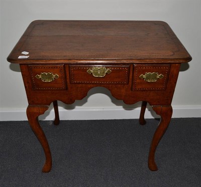 Lot 1688 - {} A George III oak lowboy with three drawers above an arched apron raise on cabriole legs,...