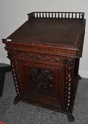 Lot 1710 - A Victorian carved oak Davenport with a three quarter gallery above a hinged writing slope,...