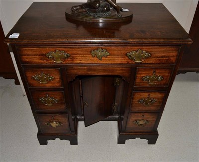 Lot 1732 - A George III mahogany knee hole desk with seven drawers around a cupboard door, raised on...