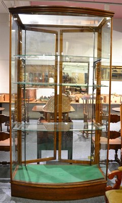 Lot 1771 - A late Victorian bow fronted glazed display cabinet with three shelves and two hinged doors,...