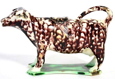Lot 12 - A Creamware cow creamer and stopper, circa 1800, with mottled manganese and green glazes, 17cm long