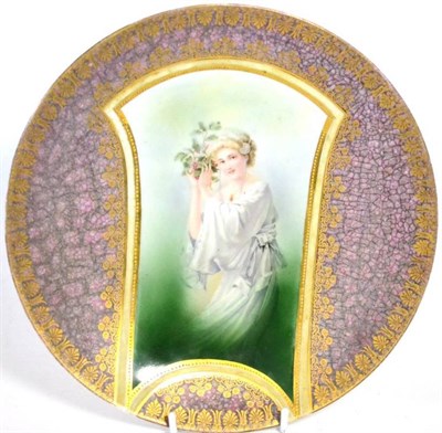 Lot 30 - A Kuznetsov porcelain wall plate, circa 1910, decorated with a maiden holding a bunch of flowers in