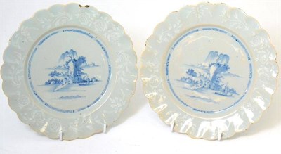 Lot 45 - A pair of English Delft plates, circa 1760, painted in blue with a boat before rocks within a...