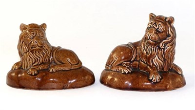 Lot 57 - A pair of treacle glazed pottery figures of lions, possibly Brameld, circa 1840, the recumbent...