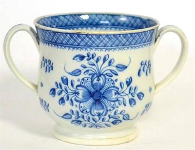 Lot 59 - A pearlware loving cup, circa 1780, painted in overglaze blue with stylised foliage below a lattice