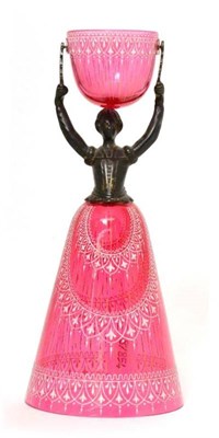 Lot 141 - A cranberry glass and pewter wager cup, modelled as a lady wearing a crinoline holding a cup...