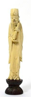 Lot 249 - A Chinese ivory figure of a bearded man, 19th century, standing in flowing robes holding a piece of