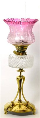 Lot 304 - A Victorian brass oil lamp base with foliate edged cranberry glass shade, glass chimney, cut...