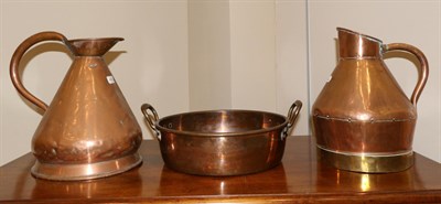 Lot 409 - A twin handled copper pan, 19th century, 46cm wide; and two copper jugs, 39cm high