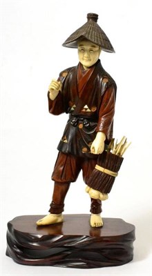 Lot 448 - A Japanese ivory and wood okimono, Meiji period, as a farmer with a straw hat carrying a basket...