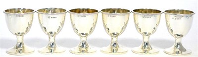 Lot 525 - A set of six Victorian silver egg cups, Charles Boyton, London 1871, plain with bead border,...