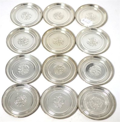 Lot 529 - A set of twelve Georg Jensen silver coasters, decorated to the centre with a foliate roundel,...